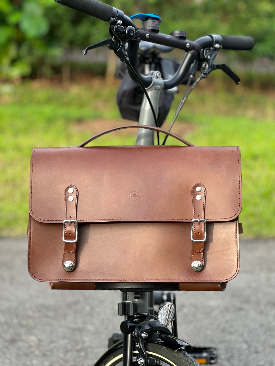 Front view of the brown Souma leather briefcase mounted on a Brompton bicycle