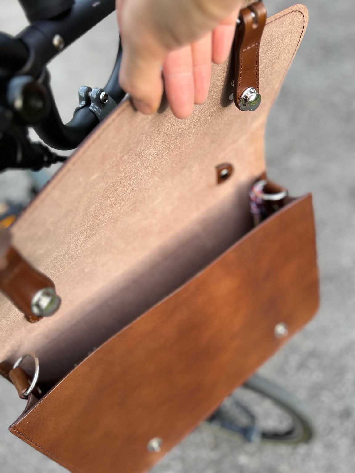 Open brown Souma leather briefcase showing the inside of the flap and closure hardware