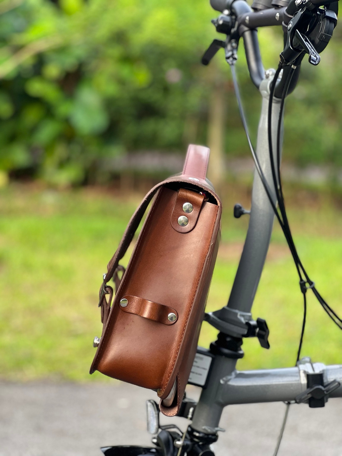 Side profile of the brown Souma leather briefcase mounted on a Brompton