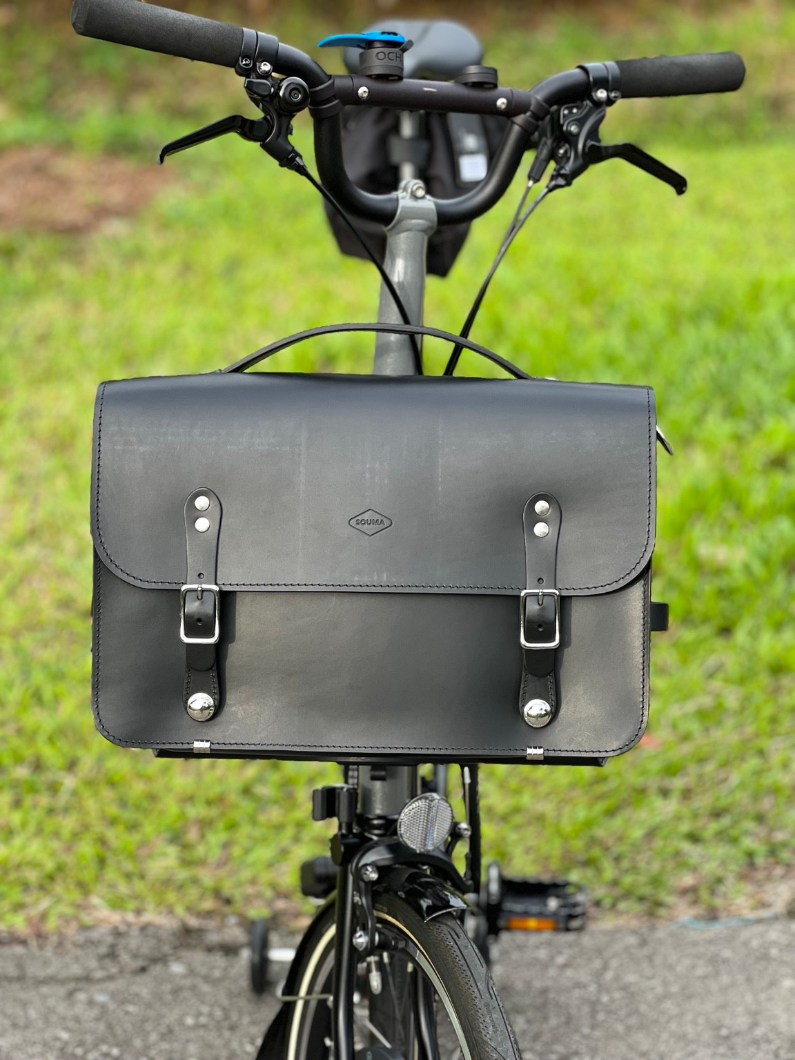 Black Souma Leather camera bag mounted on a Brompton, front view