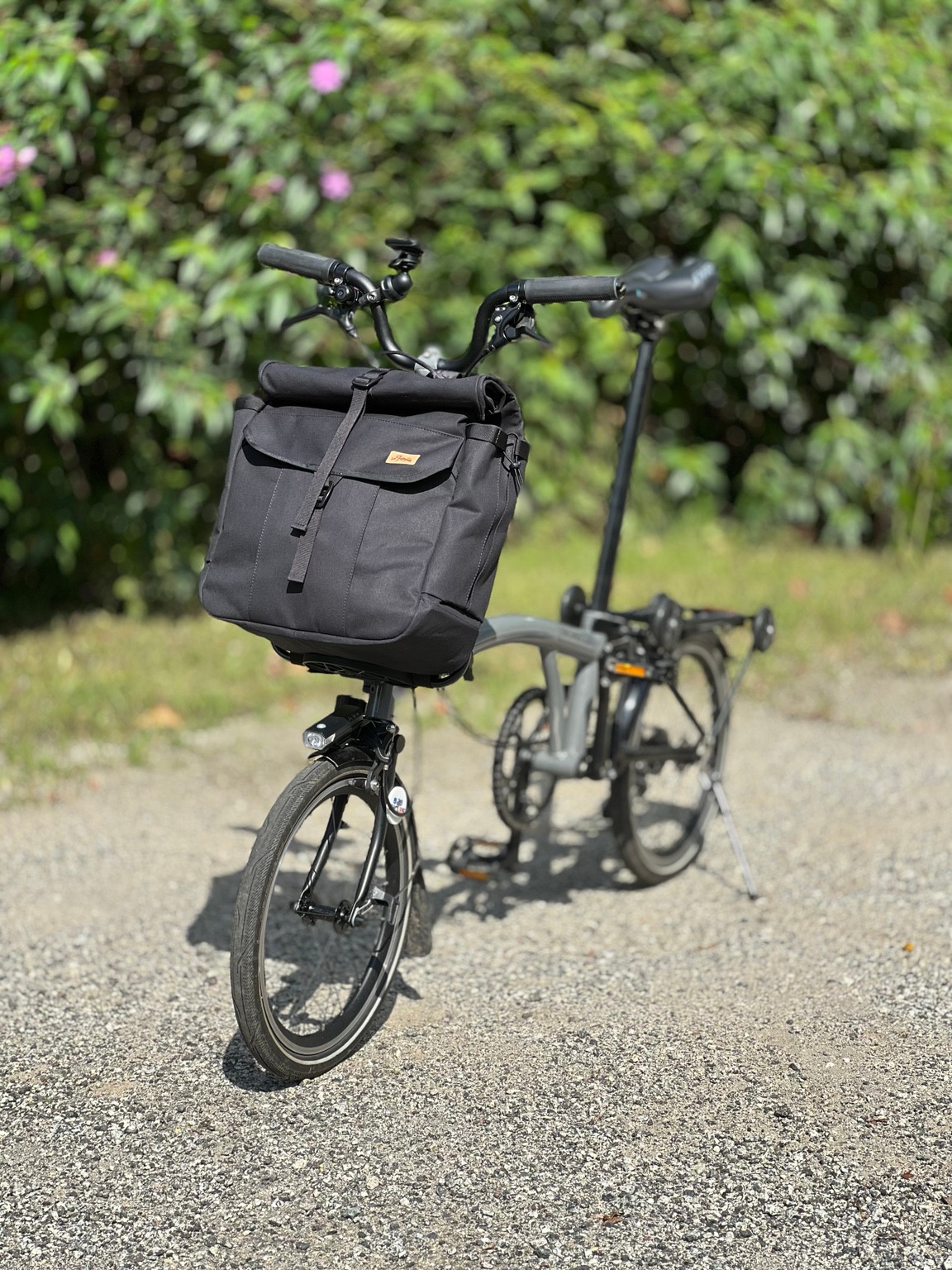 Three-quarter view of the black Bropack on a grey Brompton outdoors