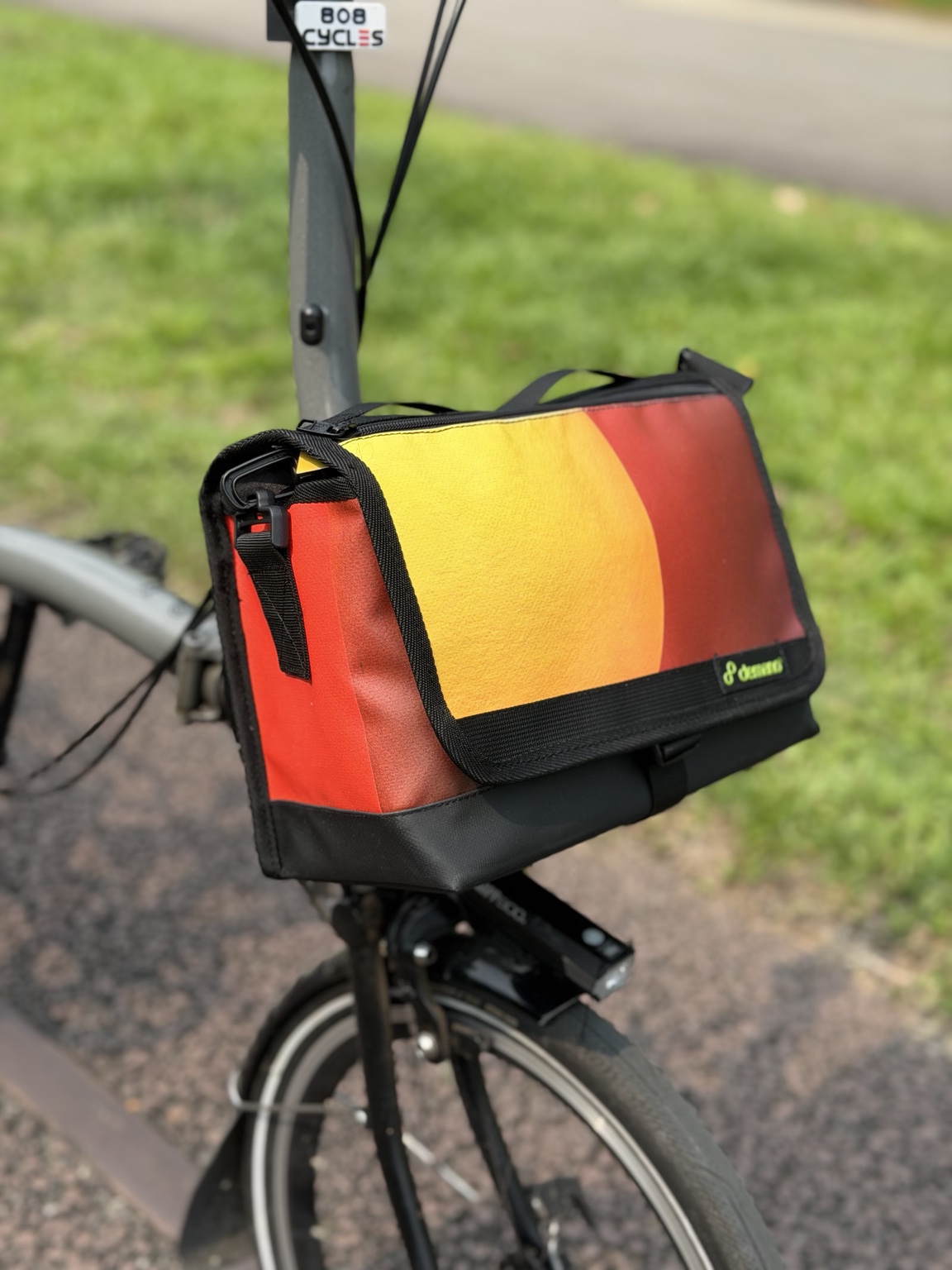 Left three-quarter view of Demano Ribera 1710 showing its yellow-orange curved flap and bright red side panel with darker burgundy stripe.