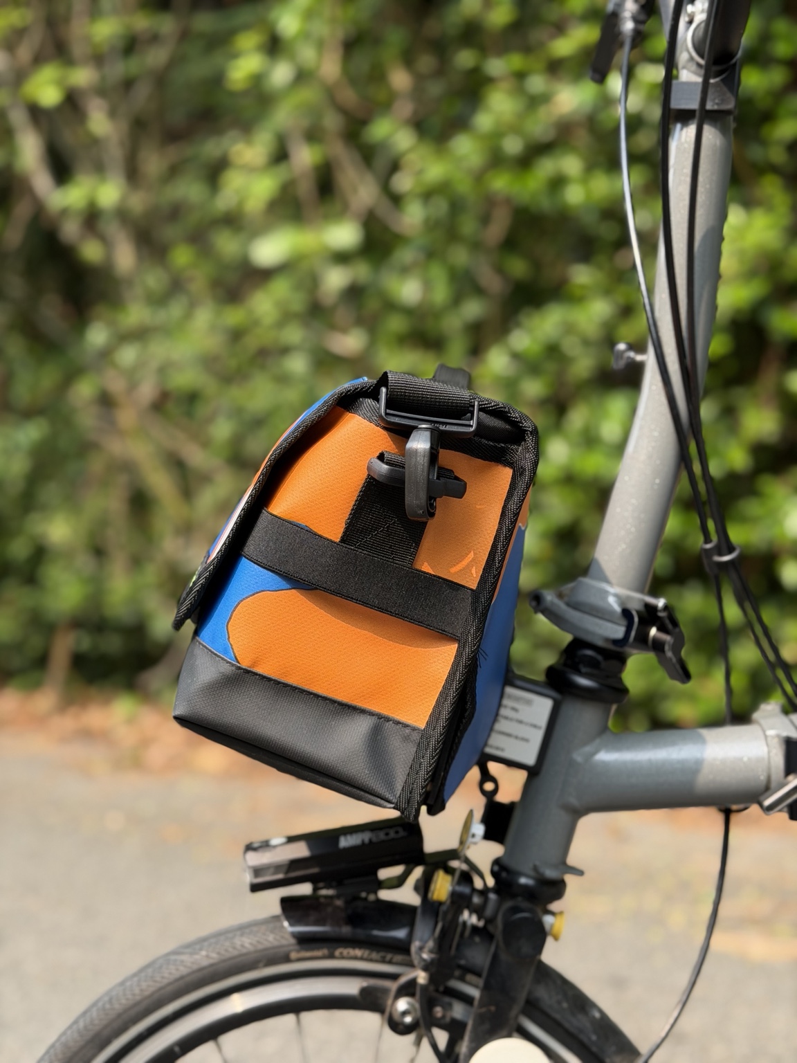 Right-side profile of Demano Ribera 1706 showing black strap hardware and horizontal webbing over orange-and-blue banner canvas.