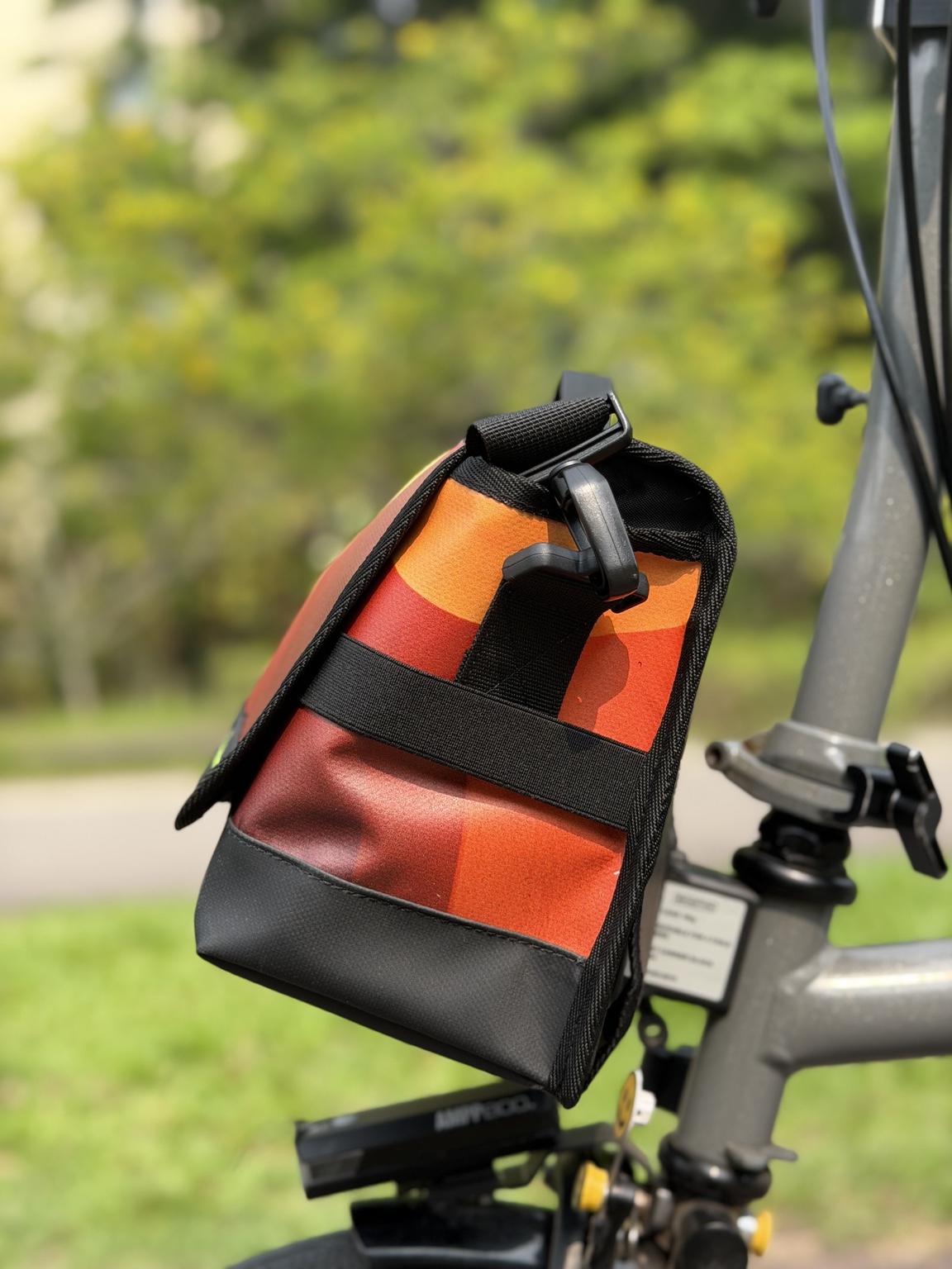 Right-side profile of Demano Ribera 1710 with orange and red curved print, black elastic strap, hardware and reinforced black base.