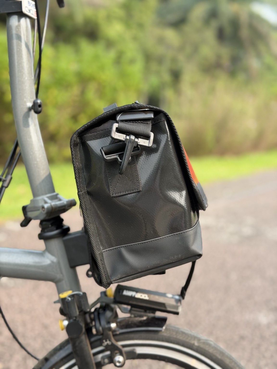 Left-side profile of Demano Ribera 1704 with black strap hardware, glossy reclaimed banner material and reinforced black base.