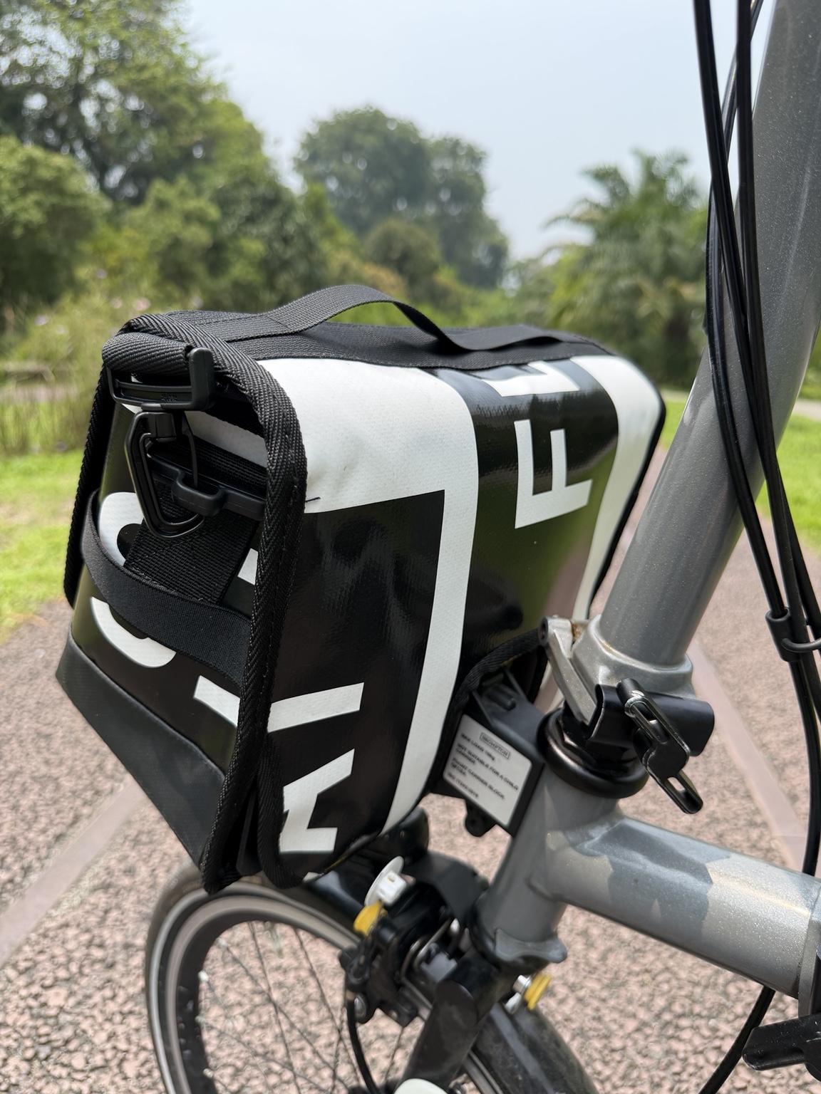 Rear-side angle of Demano Ribera 1709 showing bold cropped black-and-white banner lettering beside the actual grey Brompton stem and cables.