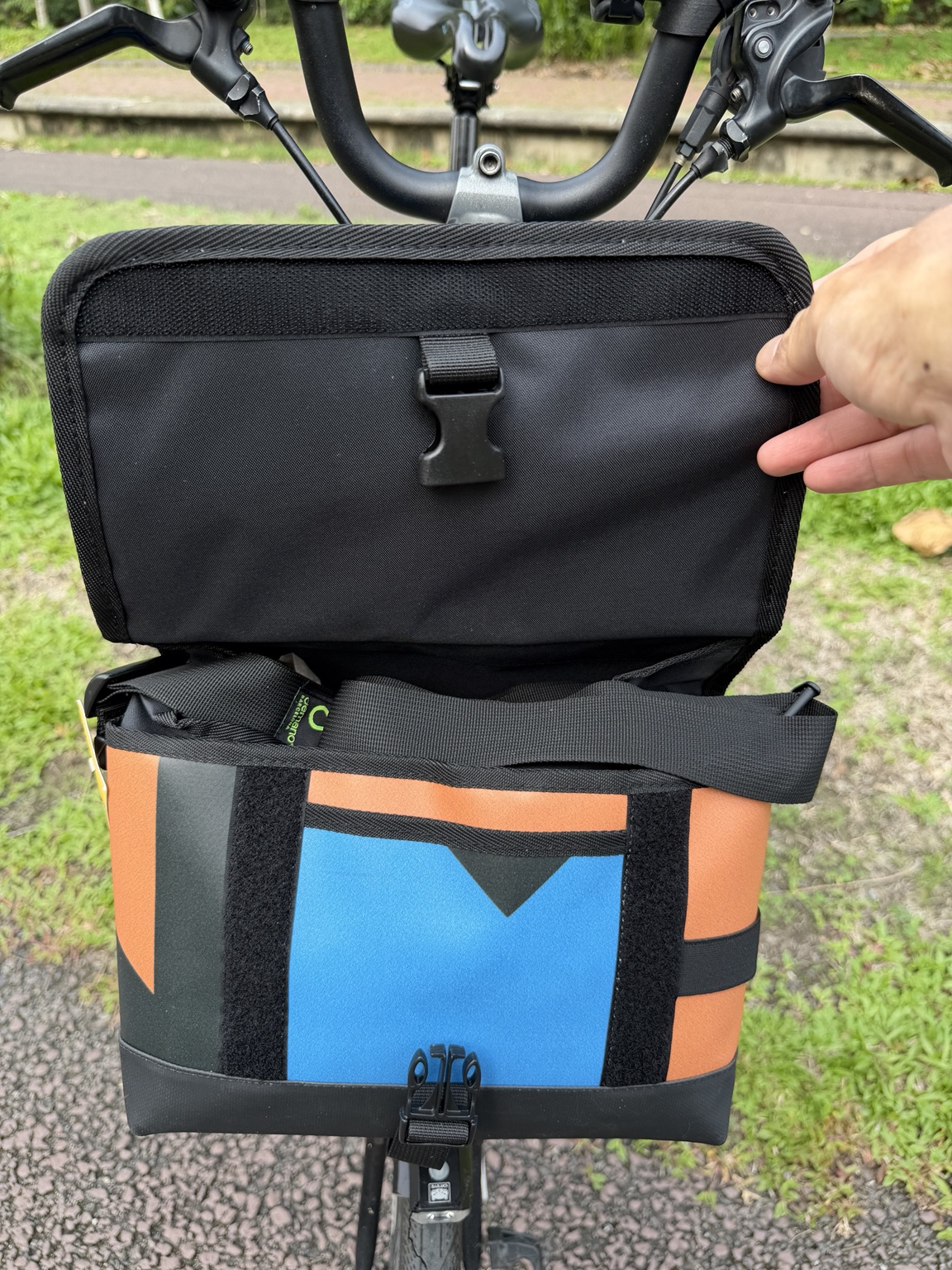 Demano Ribera 1705 with the flap held open, showing black lining, a blue and orange front pocket panel, shoulder strap, hook-and-loop strips and buckle.