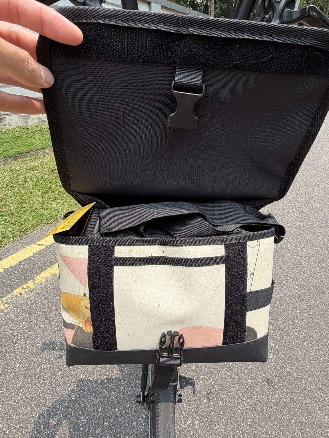 Actual Demano Ribera 1708 with its flap held open, showing black lining, front fastening, cream printed canvas and shoulder strap.