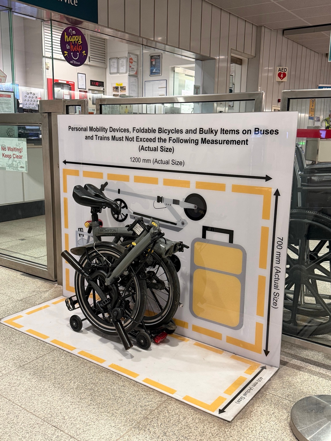 Folded Brompton within a Singapore public transport size checker marked 120 cm by 70 cm by 40 cm.