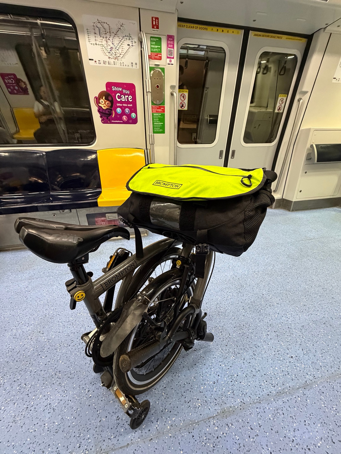 Bob’s Brompton with a yellow-topped front bag inside an MRT carriage in Singapore.