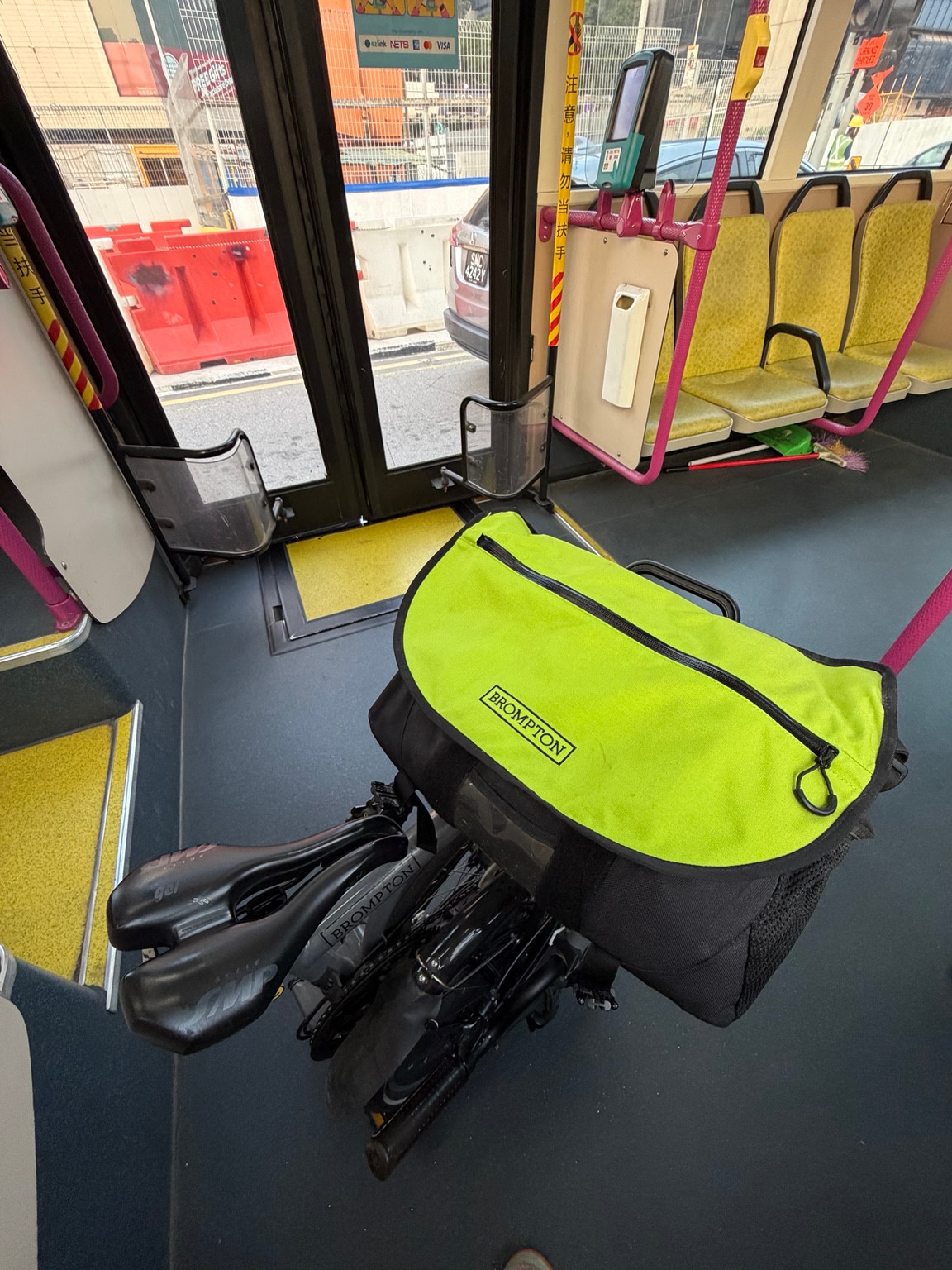 Bob’s Brompton with a yellow-topped front bag inside a Singapore public bus.