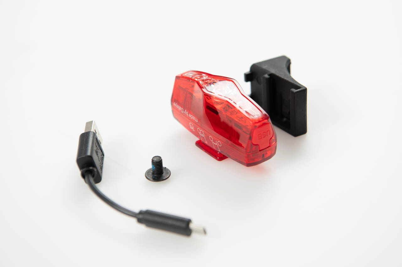 Brompton Cateye VIZ150 Q103799 rear light with black saddle bracket, mounting screw and Micro-USB charging cable on white background