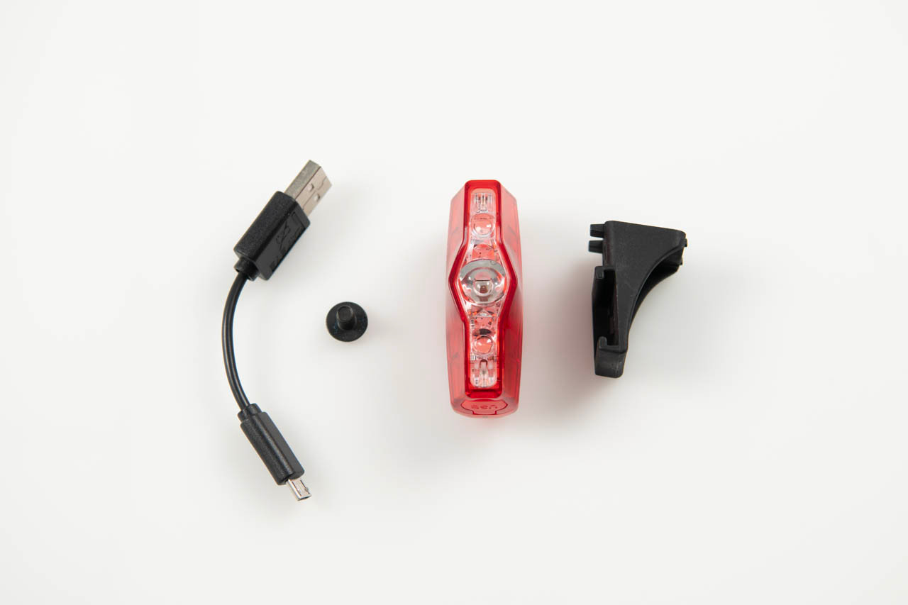 Brompton Cateye VIZ150 Q103799 rear light, saddle bracket, mounting screw and Micro-USB cable laid out on white background