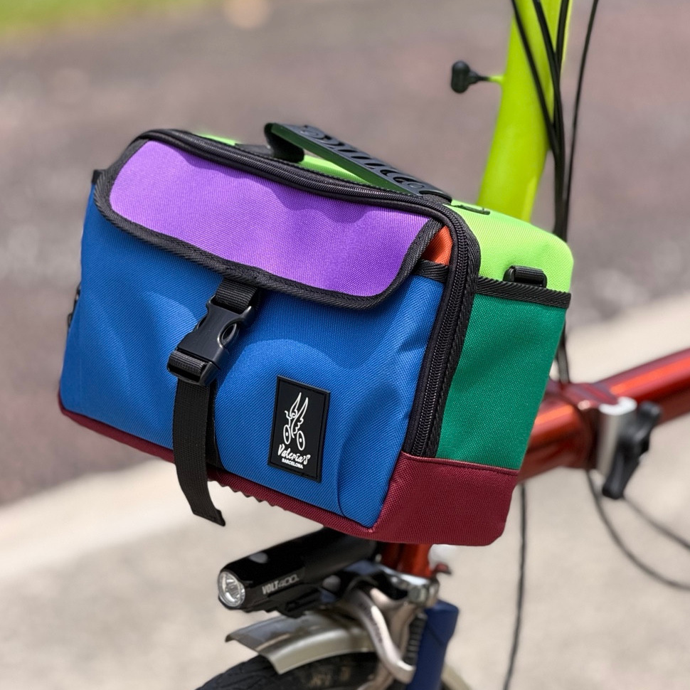 Valeria’s Cris Mini #01 5L bag mounted on a Brompton, with blue front, purple flap, green side panels and burgundy base