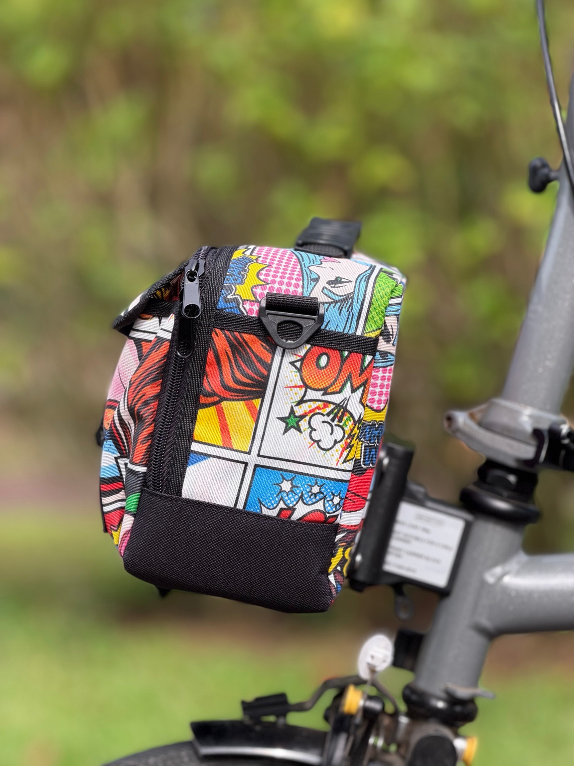Side view of Valeria’s Cris Mini #02 showing multicolour comic panels, a shoulder-strap attachment ring and black lower panel