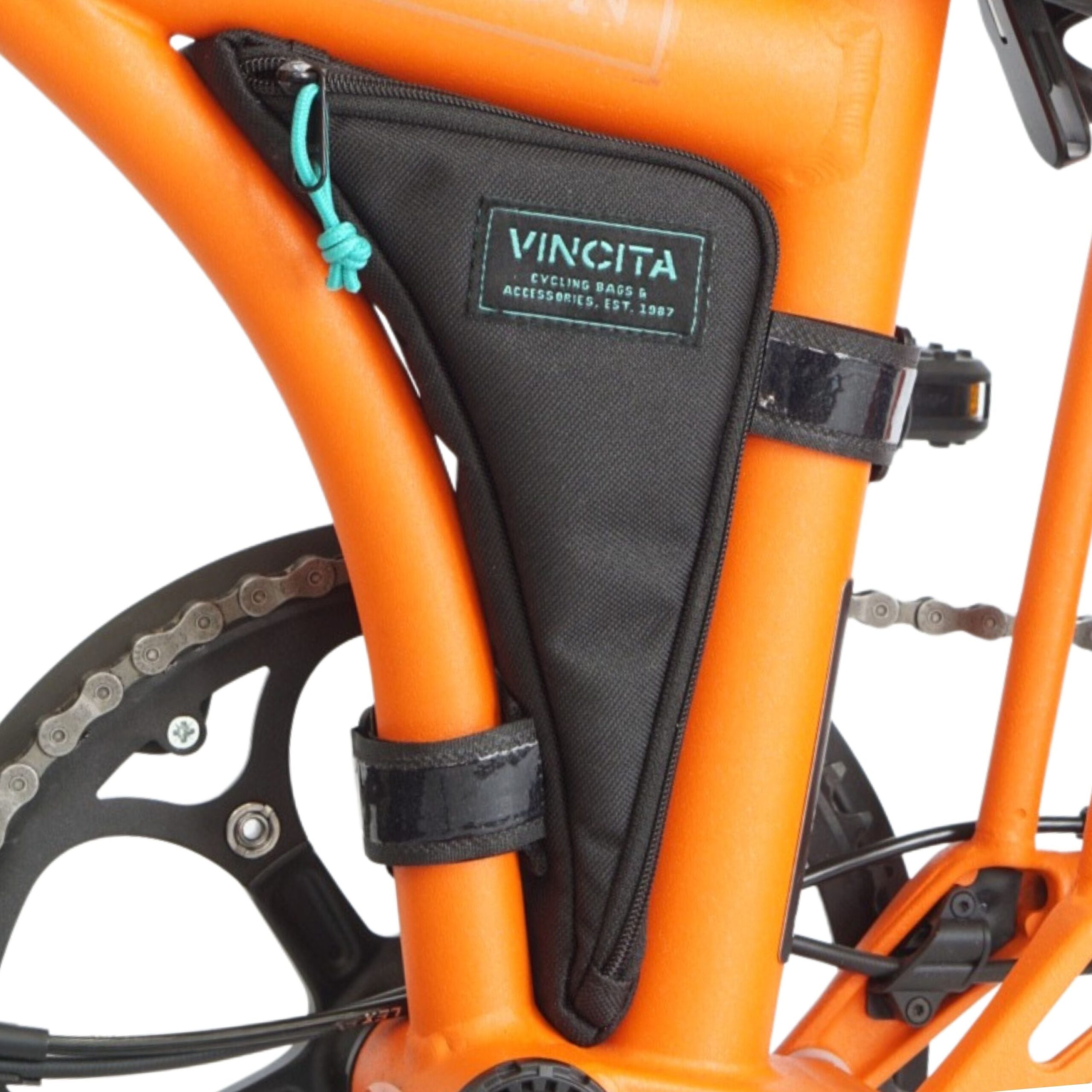 Black Vincita Boomerang Bag installed in the triangular frame space of an orange Brompton G Line